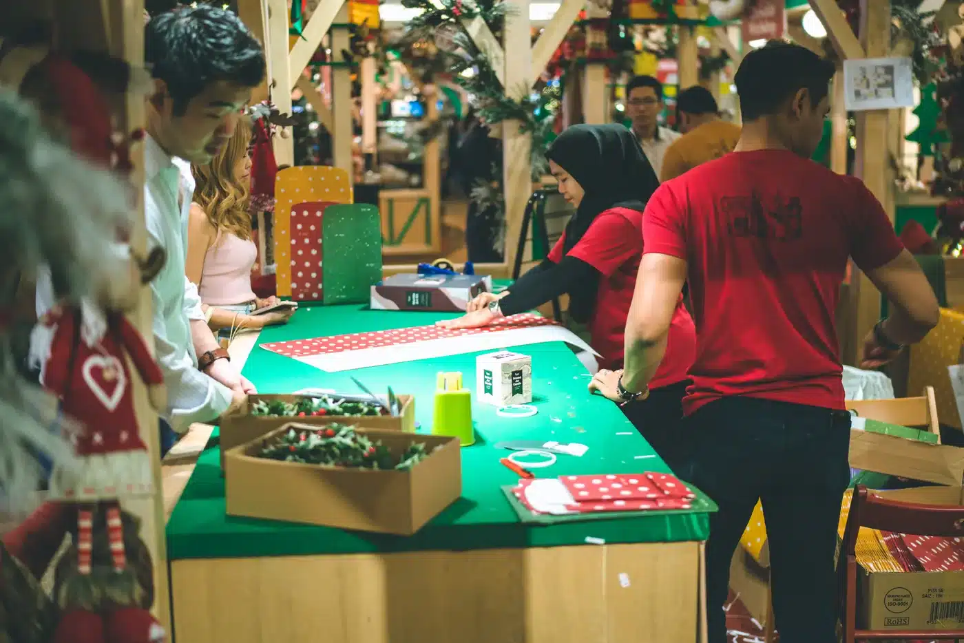 Personnes réunies autour d’une table avec du papier cadeau et des décorations de Noël